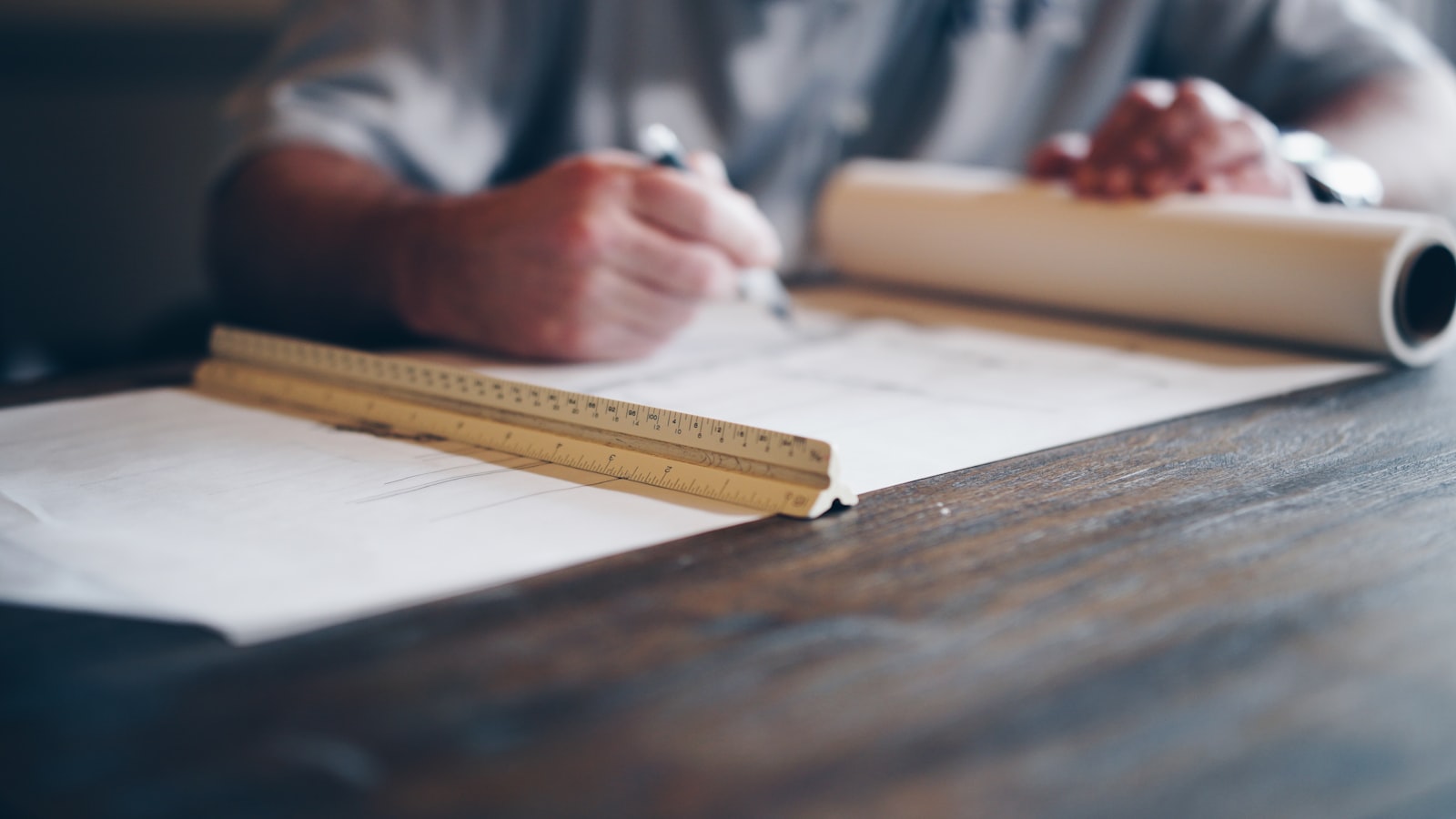 Hands working over a set of architectural drawings — B&B Building and Design studio